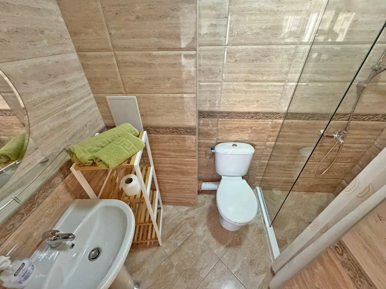 Современная ванная комната с душевой и туалетом, стильный интерьер Современная ванная комната с душевой кабиной, умывальником и стильным декором, идеальная для апартаментов в Болгарии.