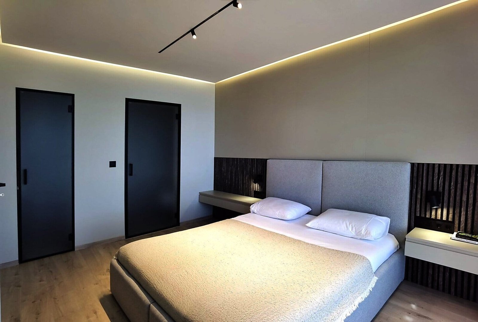 Современная спальня с уютной кроватью, минималистичным дизайном и мягким освещением в интерьере недвижимости в Болгарии.