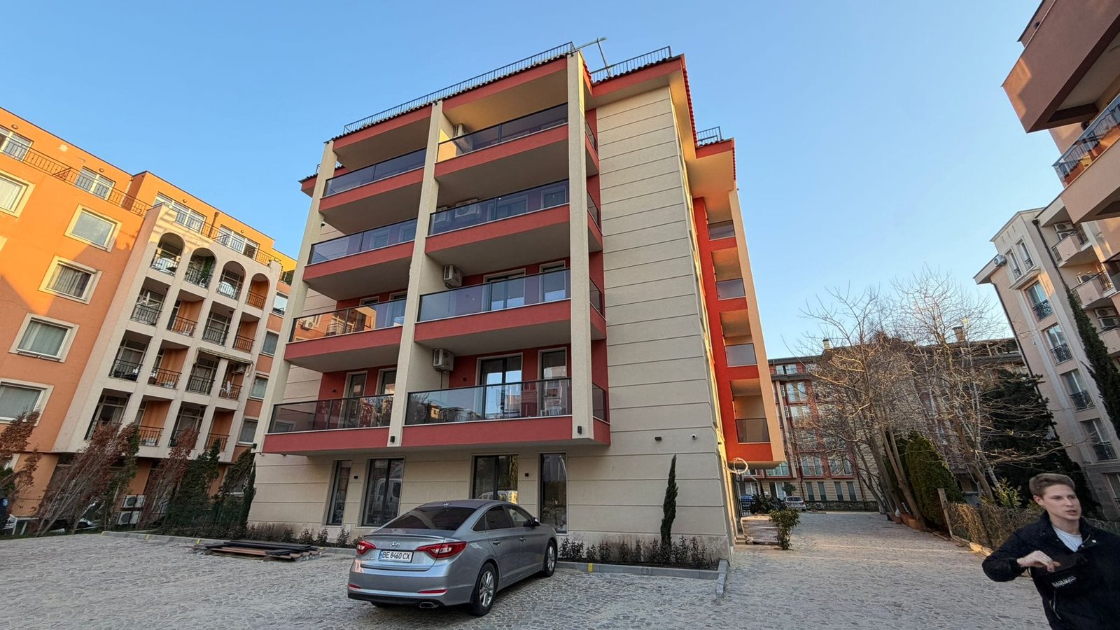 Современное жилое здание с парковкой и зелеными насаждениями Современное жилое здание с балконами в Болгарии, окруженное парковкой и зелеными насаждениями. Подходит для покупки недвижимости.