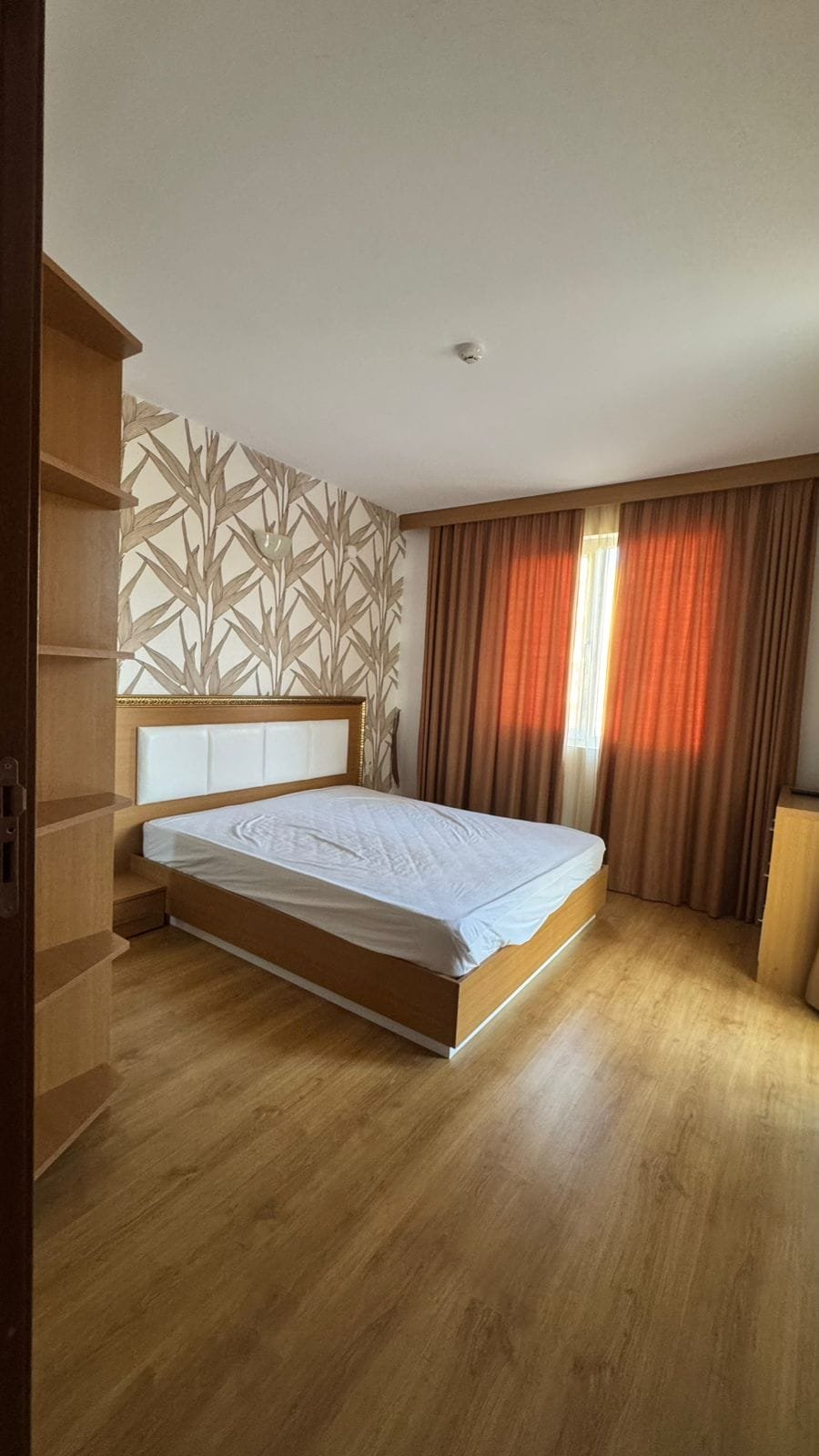 Современная спальня с деревянным полом, светлыми стенами и гардеробом, идеальная для покупки недвижимости в Болгарии.