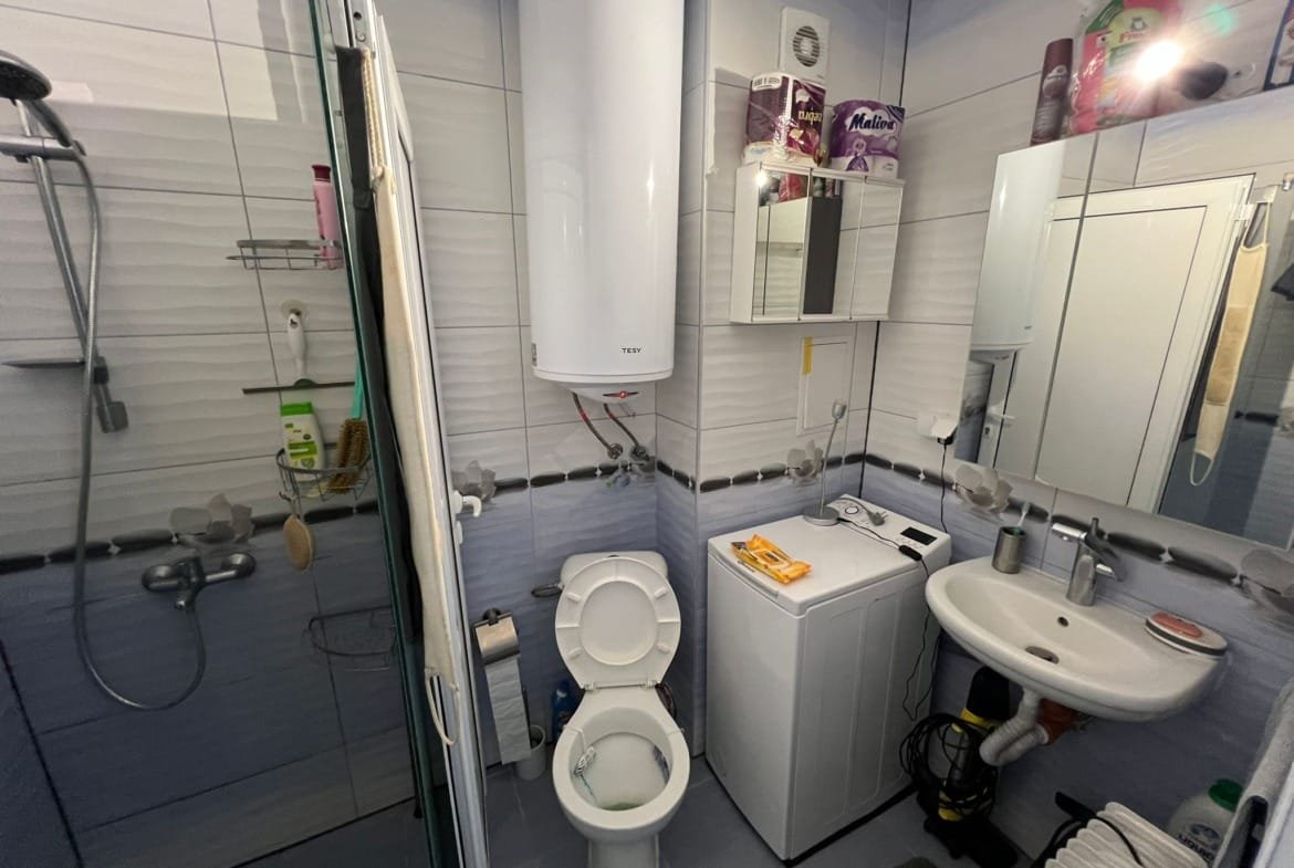 Современная ванная комната с душевой, унитазом, стиральной машинкой и зеркалом. Идеально для комфортной жизни в Болгарии.