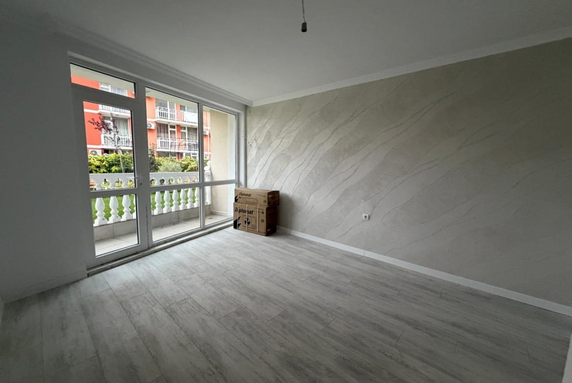 Светлая комната с большими окнами, оформленная в нейтральных тонах, готовая для продажи недвижимости в Болгарии.