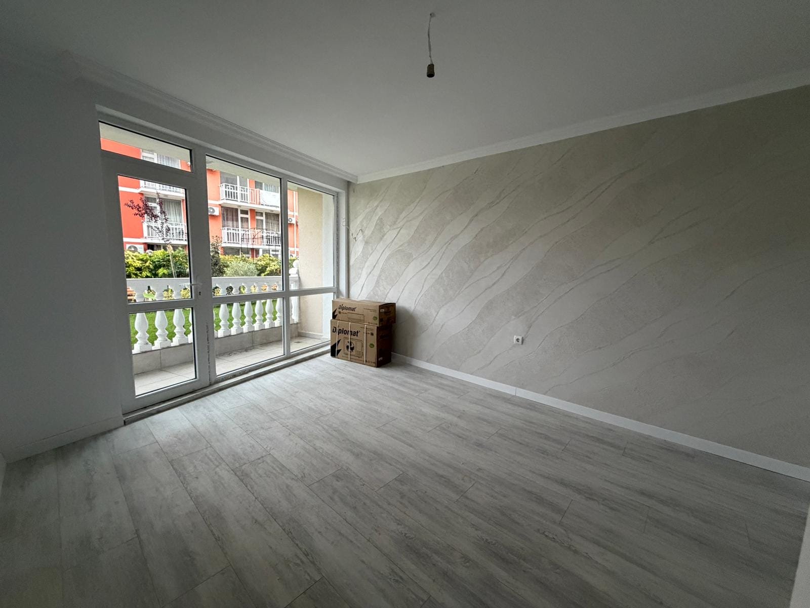 Светлая комната с большими окнами, оформленная в нейтральных тонах, готовая для продажи недвижимости в Болгарии.