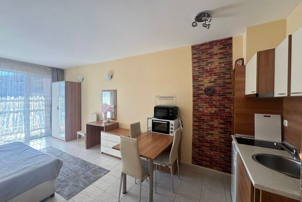 Современная квартира с кухней и обеденной зоной, светлые тона, большие окна, вид на балкон, идеальная для жизни в Болгарии.