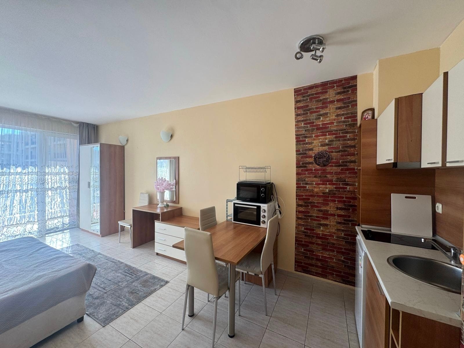 Современная квартира с кухней и обеденной зоной, светлые тона, большие окна, вид на балкон, идеальная для жизни в Болгарии.