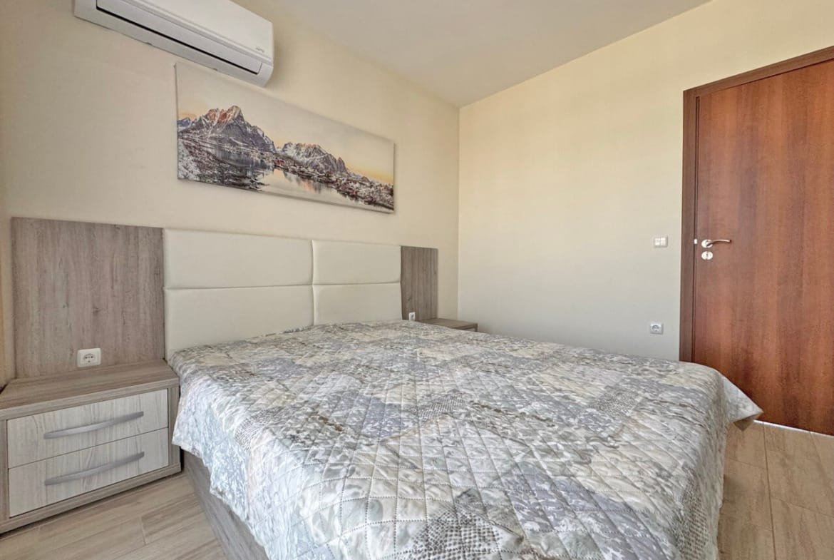 Современная спальня с деревянной мебелью, двуспальной кроватью и настенным искусством, светлые стены, холодные тона.