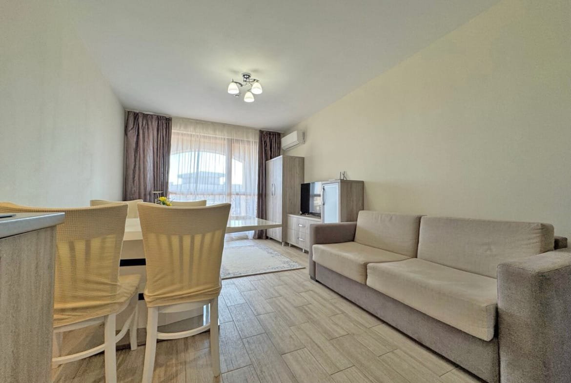 Современный интерьер квартиры с диваном, обеденным столом и светлыми шторами, создающий уютную атмосферу.