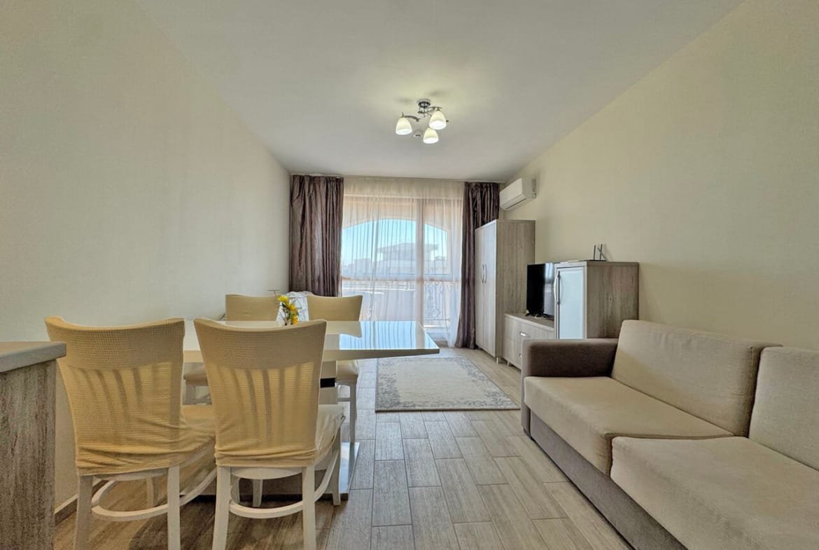 Современный интерьер квартиры с обеденным столом, удобным диваном и телевизором, светлые цвета и окна с видом.