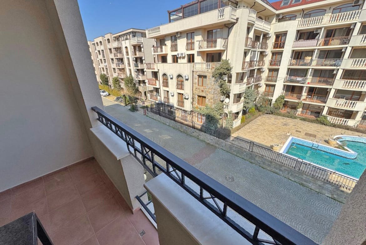 Балкон с видом на бассейн и жилые комплексы, расположенные в районе, идеально подходящий для покупки апартаментов у моря.