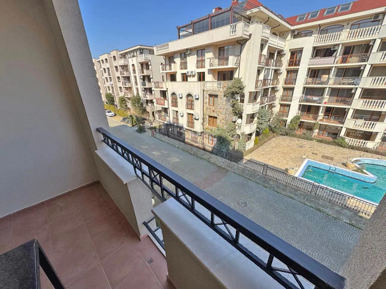 Балкон с видом на бассейн и жилые комплексы, расположенные в районе, идеально подходящий для покупки апартаментов у моря.