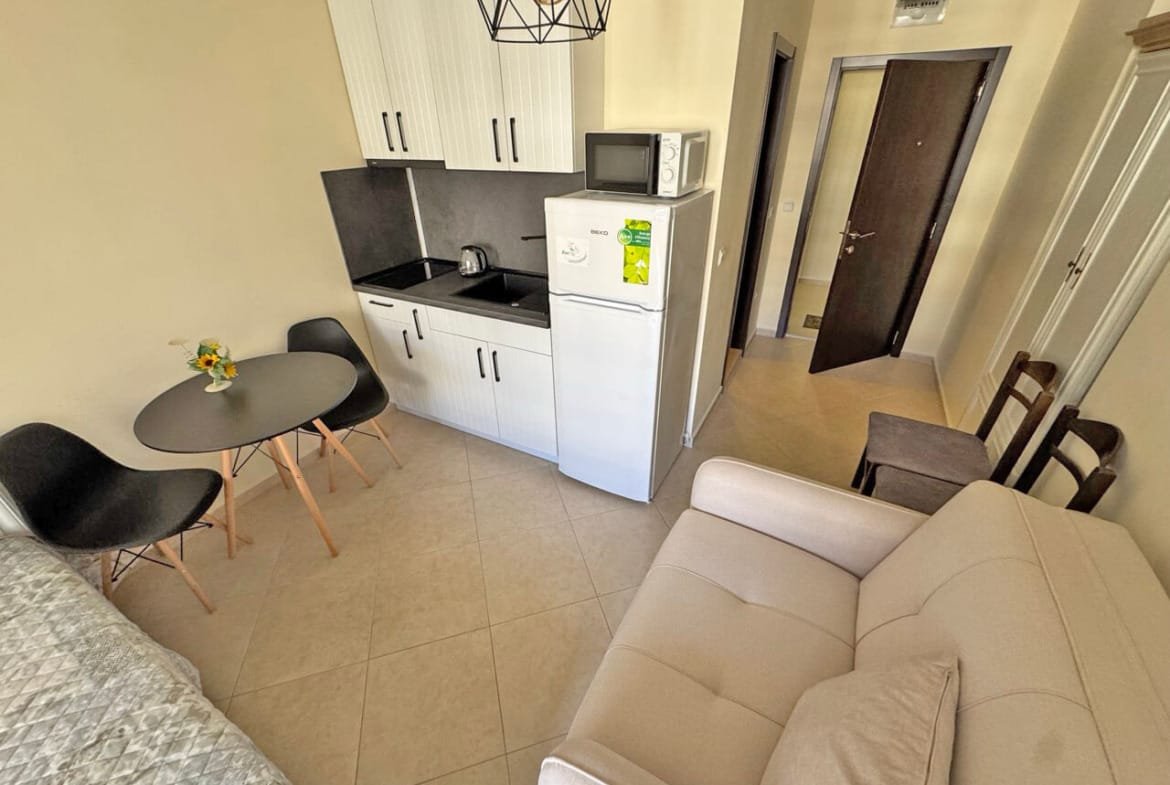 Современная кухня-студия с обеденным столом и мягким диваном, идеальная для жилья.