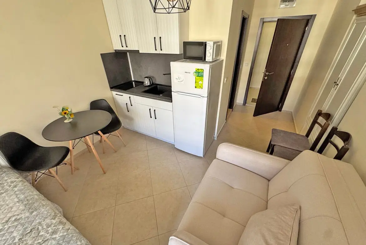 Современная кухня-студия с обеденным столом и мягким диваном, идеальная для жилья.