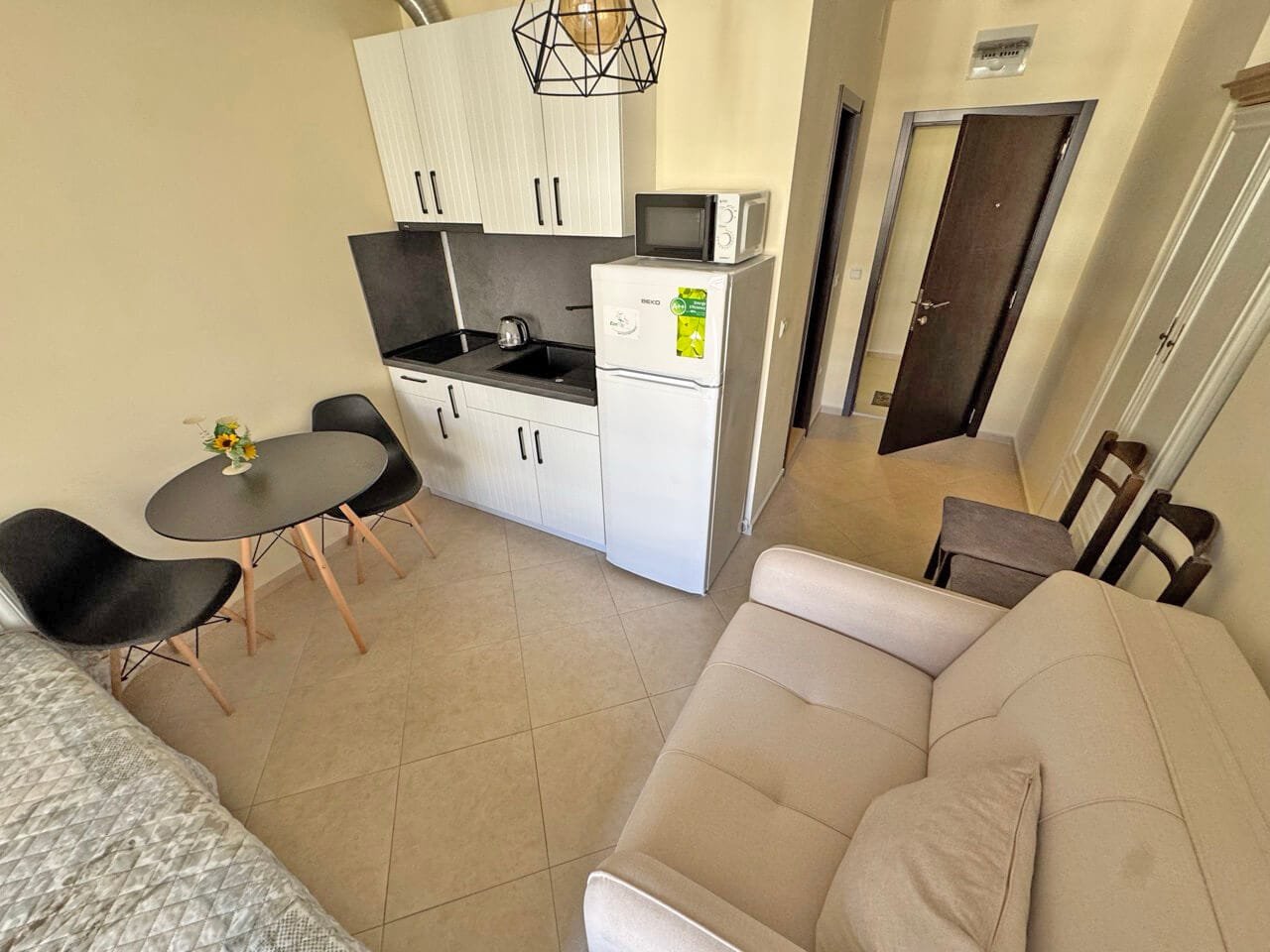 Современная кухня-студия с обеденным столом и мягким диваном, идеальная для жилья.