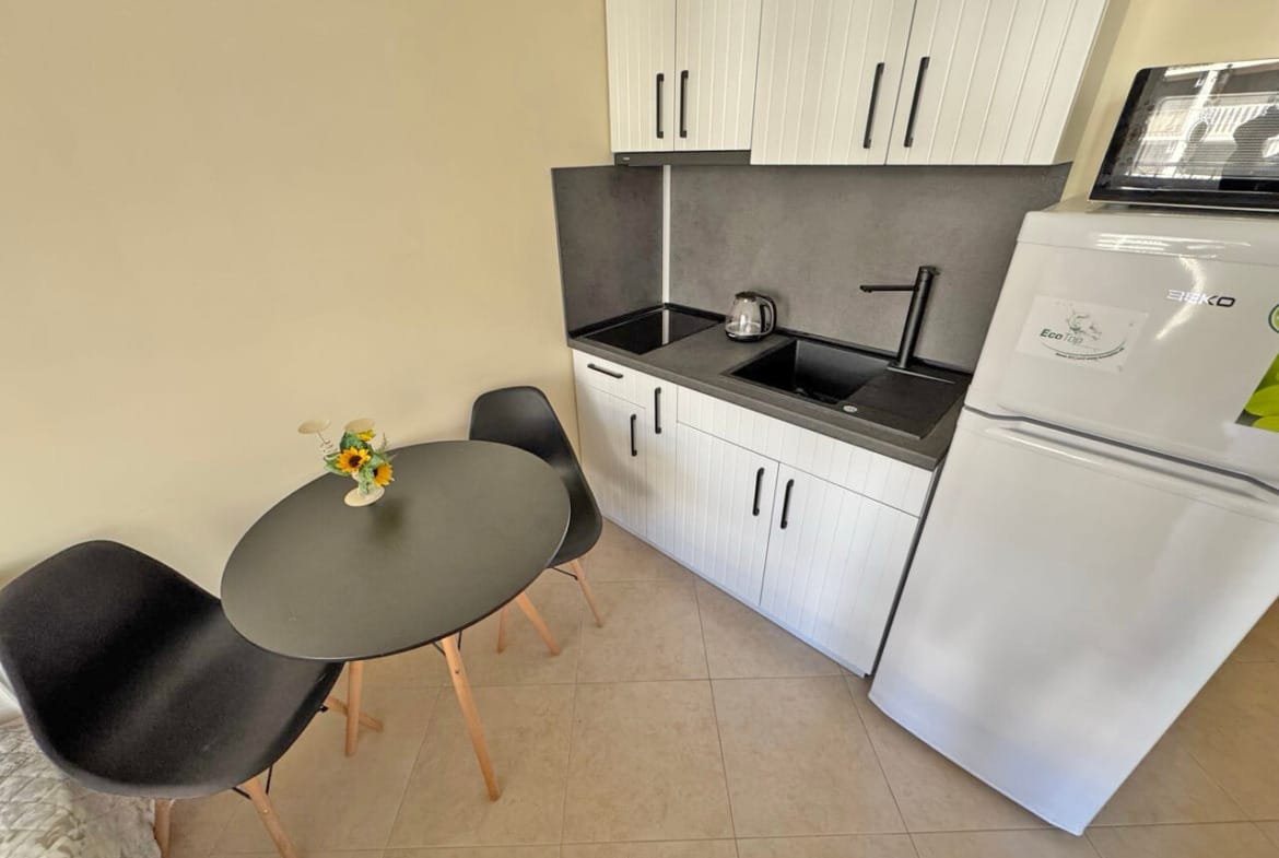 Современная кухня с черной мебелью, обеденный стол на двоих, идеальна для апартаментов у моря в Болгарии.