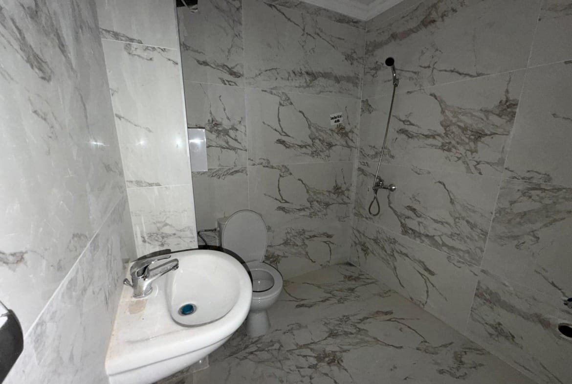 Современная ванная комната с мраморной отделкой, унитазом и душевой кабиной, идеальная для продажи недвижимости в Болгарии.