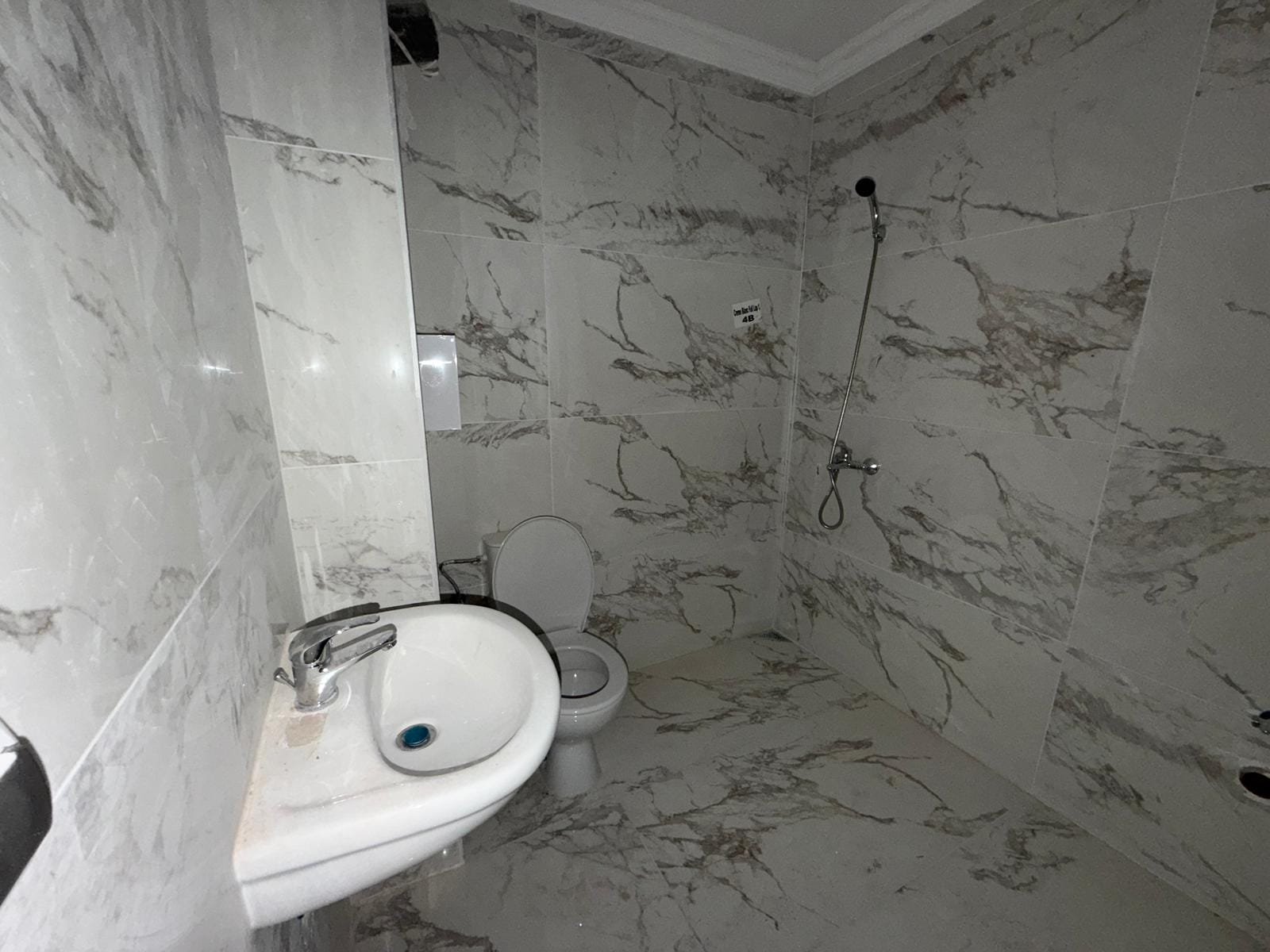 Современная ванная комната с мраморной отделкой, унитазом и душевой кабиной, идеальная для продажи недвижимости в Болгарии.