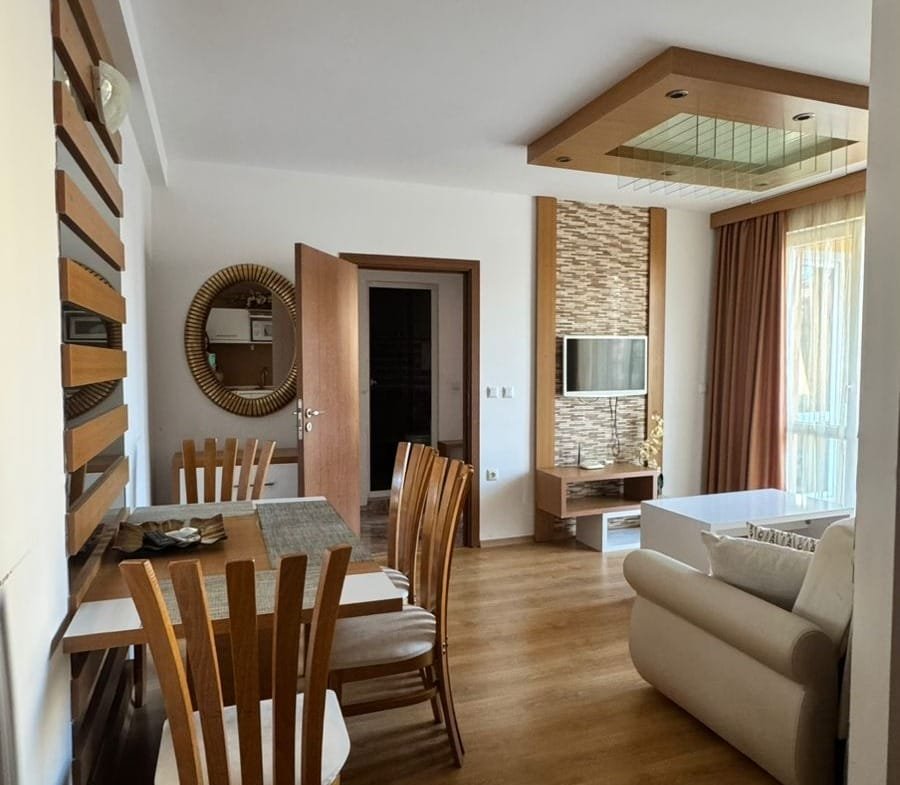 Современная гостиная с кухонным столом, деревянными стульями и мягкой мебелью в квартире в Болгарии, идеальной для продажи или аренды.