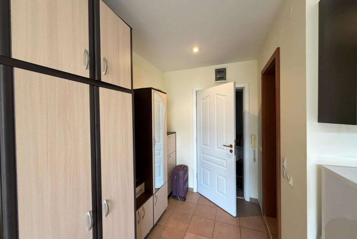 Современный коридор с встроенными шкафами и дверью, ведущей в квартиру для продажи в Болгарии.