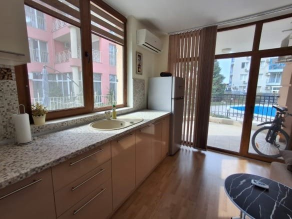 Современная кухня с открытой планировкой, стеклянными окнами, холодильником и видом на бассейн.