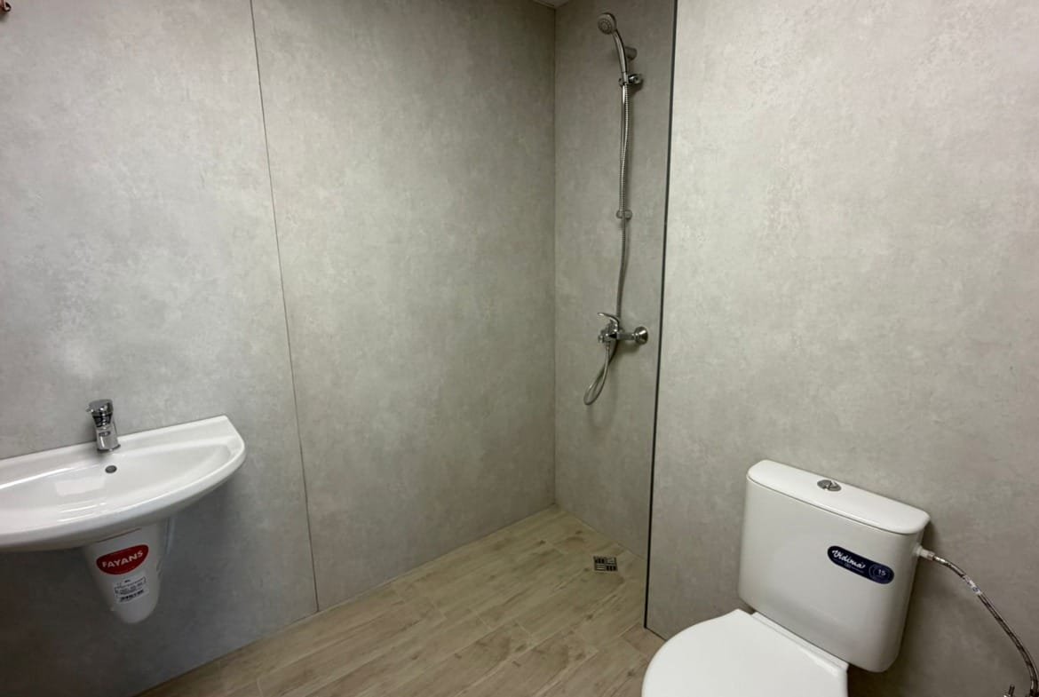 Современная ванная комната с душевой кабиной, унитазом и раковиной, оформленная в нейтральных тонах для продажи недвижимости в Болгарии.