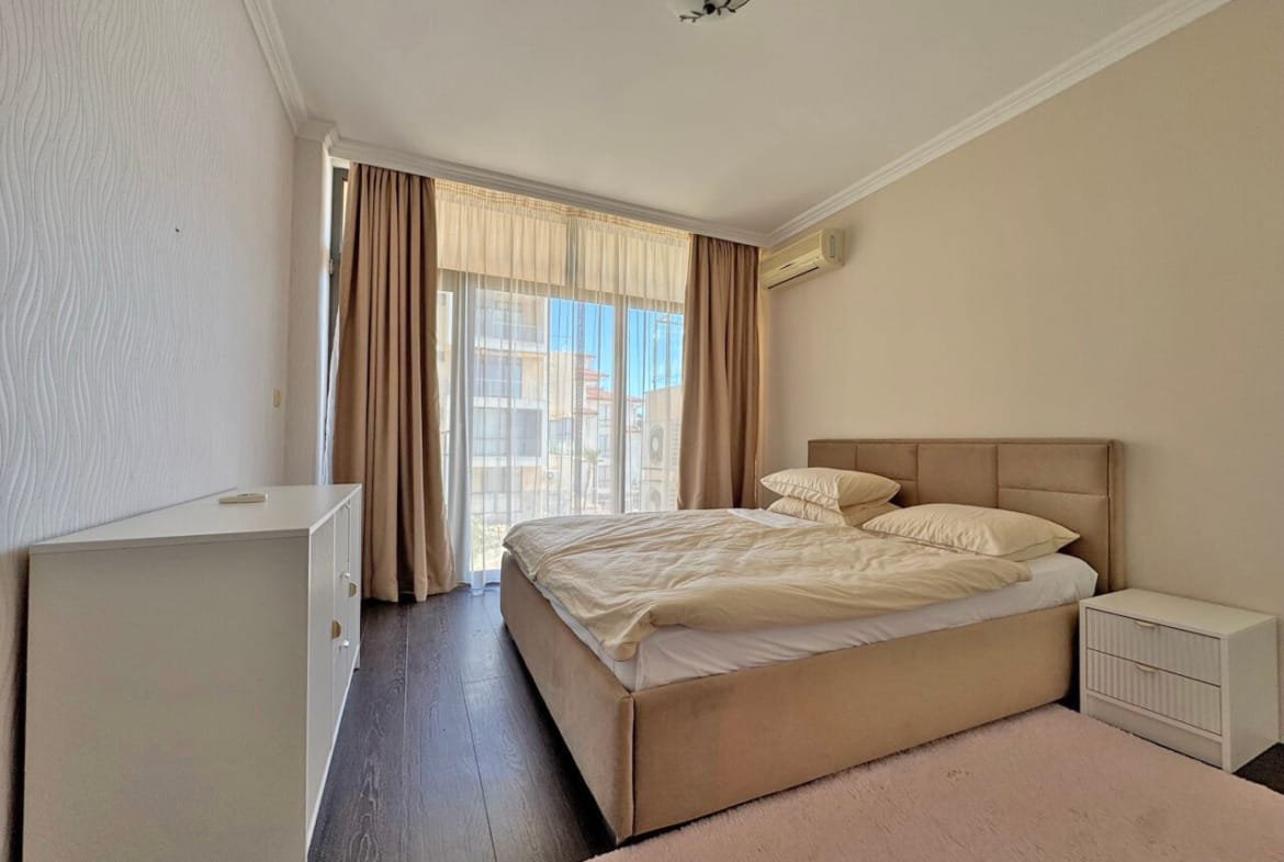 Светлая спальня с кроватью, белыми подушками и нежными шторами, окна выходят на улицу, уютный интерьер.