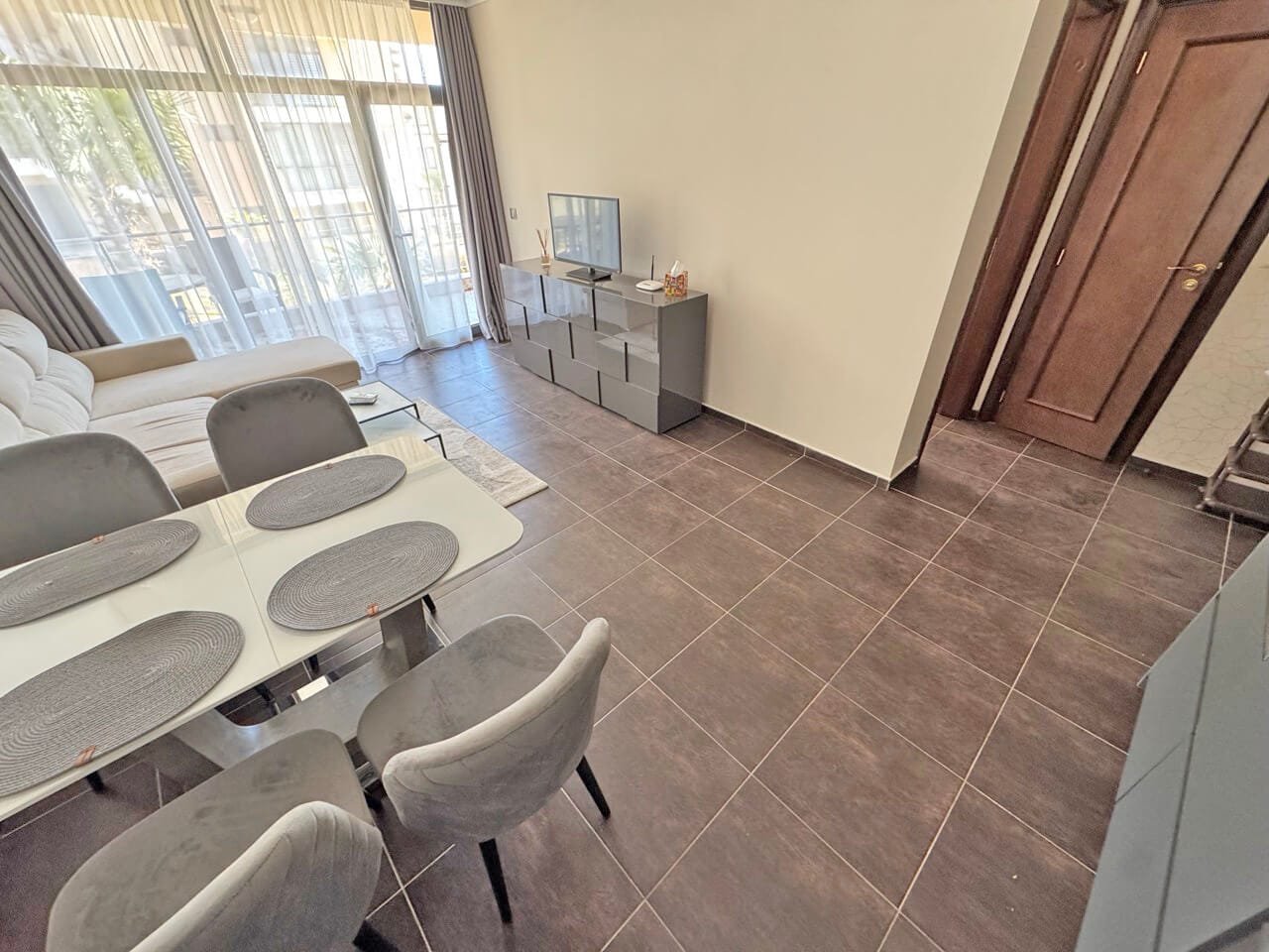 Современная гостиная с телевизором и обеденным столом Современный интерьер квартиры с гостиной, телевизором и обеденным столом, оформленный в светлых и нейтральных тонах.