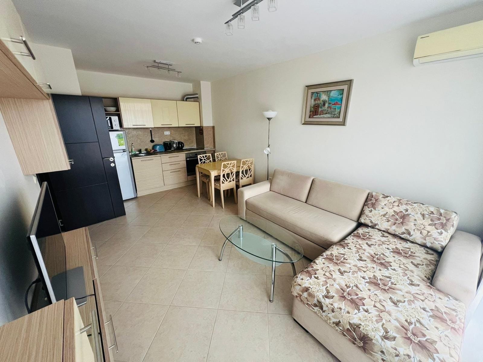 Современная квартира с уютной гостиной, столом и кухней, идеально подходящая для покупки в Болгарии.