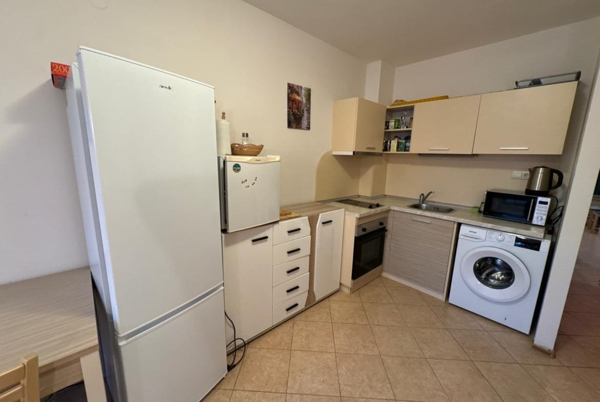 Современная кухня с белой техникой, столом, стульями и бытовыми приборами для комфортного проживания в Болгарии.