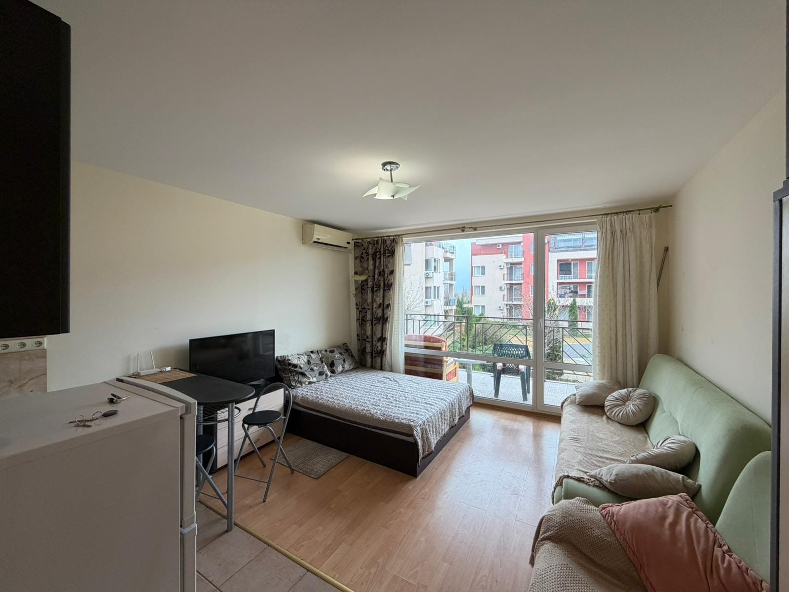 Уютная квартира-студия с балконом и современной мебелью Современная квартира в Болгарии с мебелью, балконом и освещением, подходящая для покупки или аренды недвижимости.