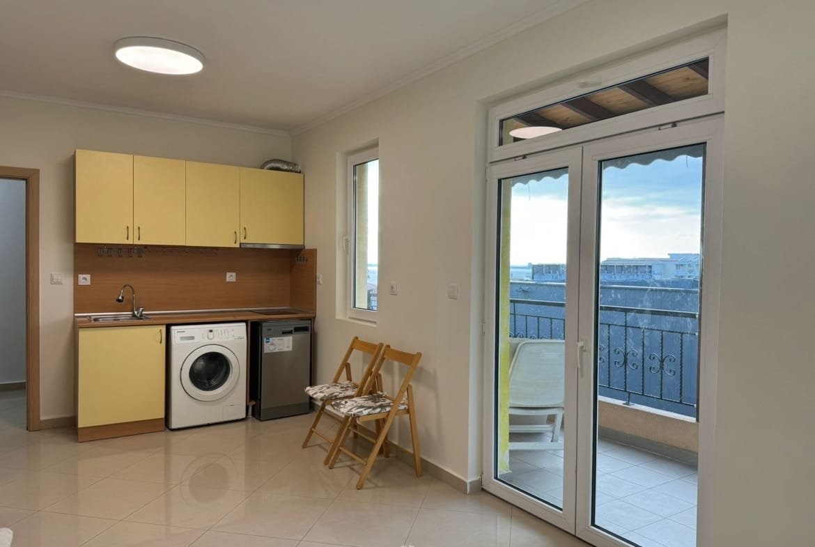 Современная кухня в квартире в Болгарии с бытовой техникой и выходом на балкон, идеальна для комфортной жизни и отдыха.