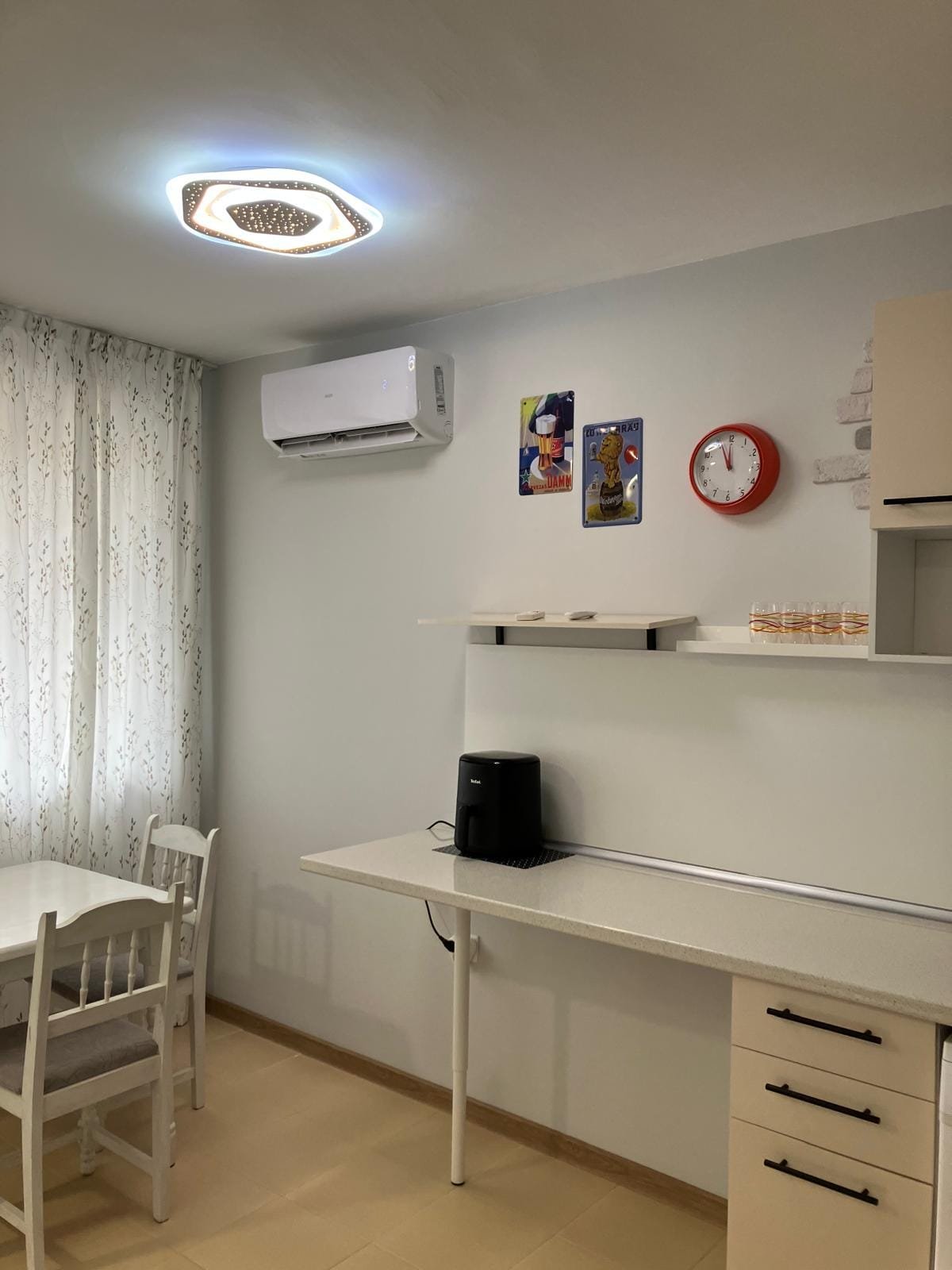 Современный интерьер квартиры с кухонным столом, кондиционером, часами и элементами декора в стиле минимализма.