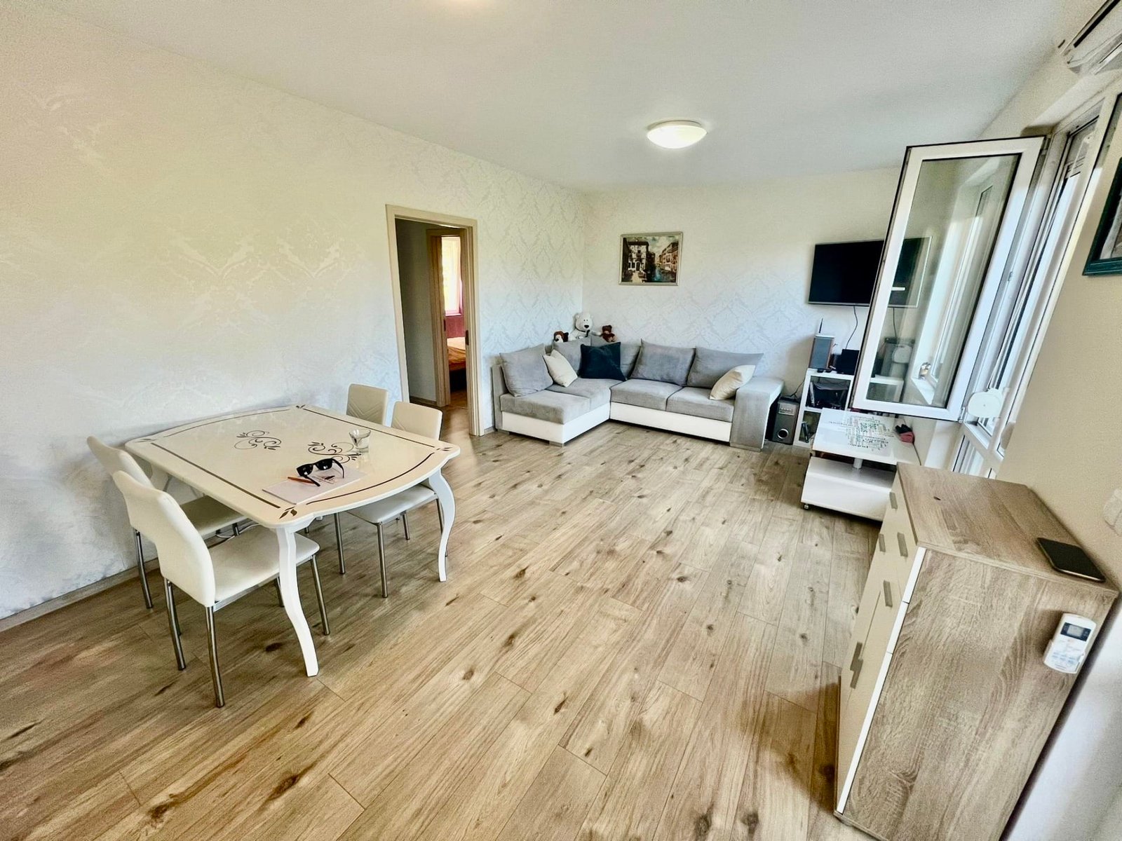 Современная гостиная в Болгарии с уютной мебелью, деревянным полом и телевизором, идеально подходящая для жизни или аренды.