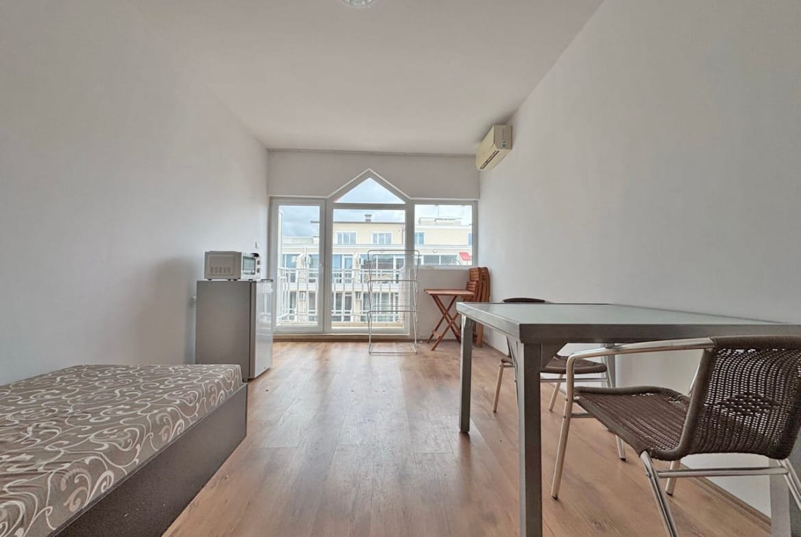 Светлая квартира с видом на море, гостиная с обеденным столом и стулом, современный интерьер в натуралистических тонах.