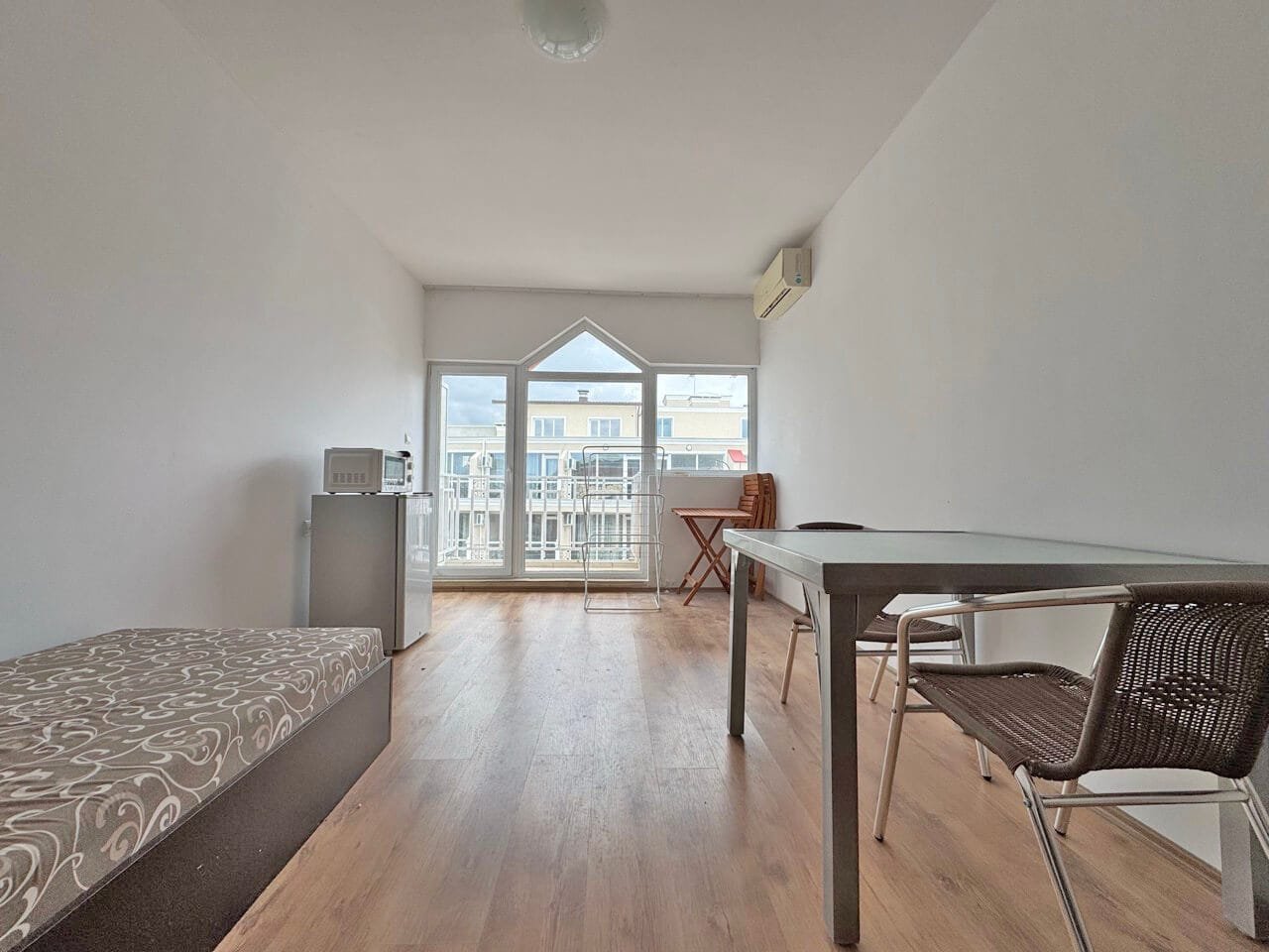 Светлая квартира с видом на море, гостиная с обеденным столом и стулом, современный интерьер в натуралистических тонах.