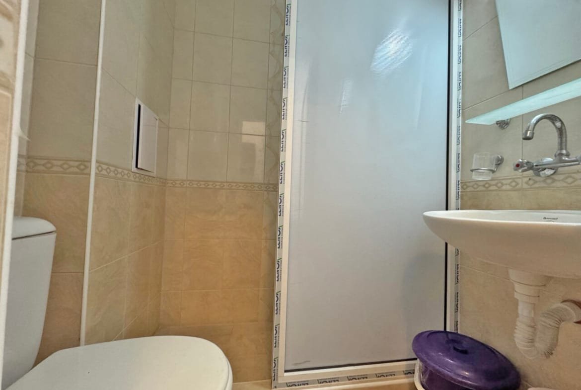 Современная ванная комната с душевой кабиной, туалетом и раковиной, подходящее жилье для апартаментов в Болгарии.