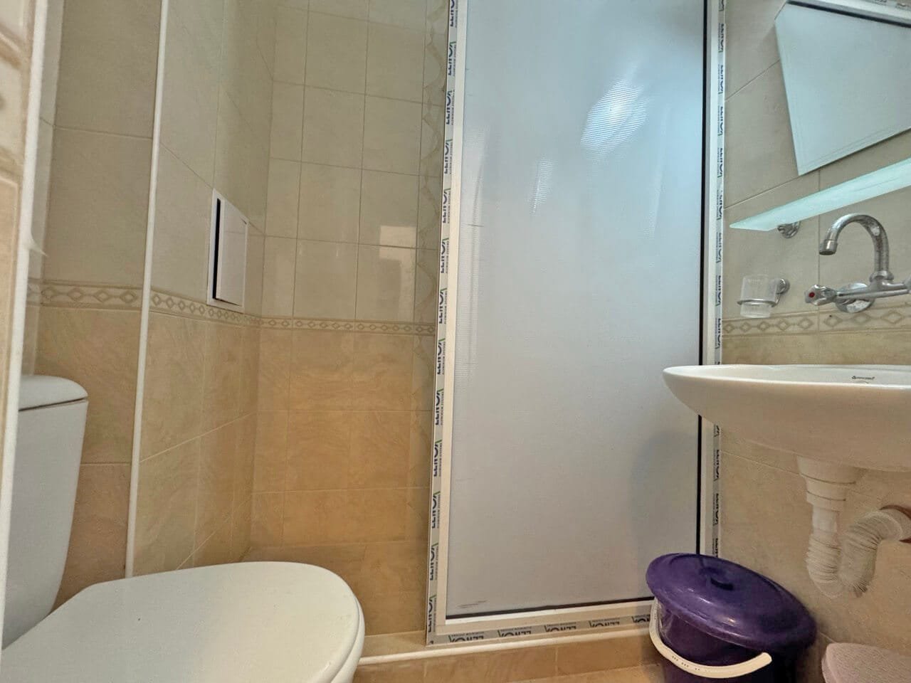 Современная ванная комната с душевой кабиной, туалетом и раковиной, подходящее жилье для апартаментов в Болгарии.