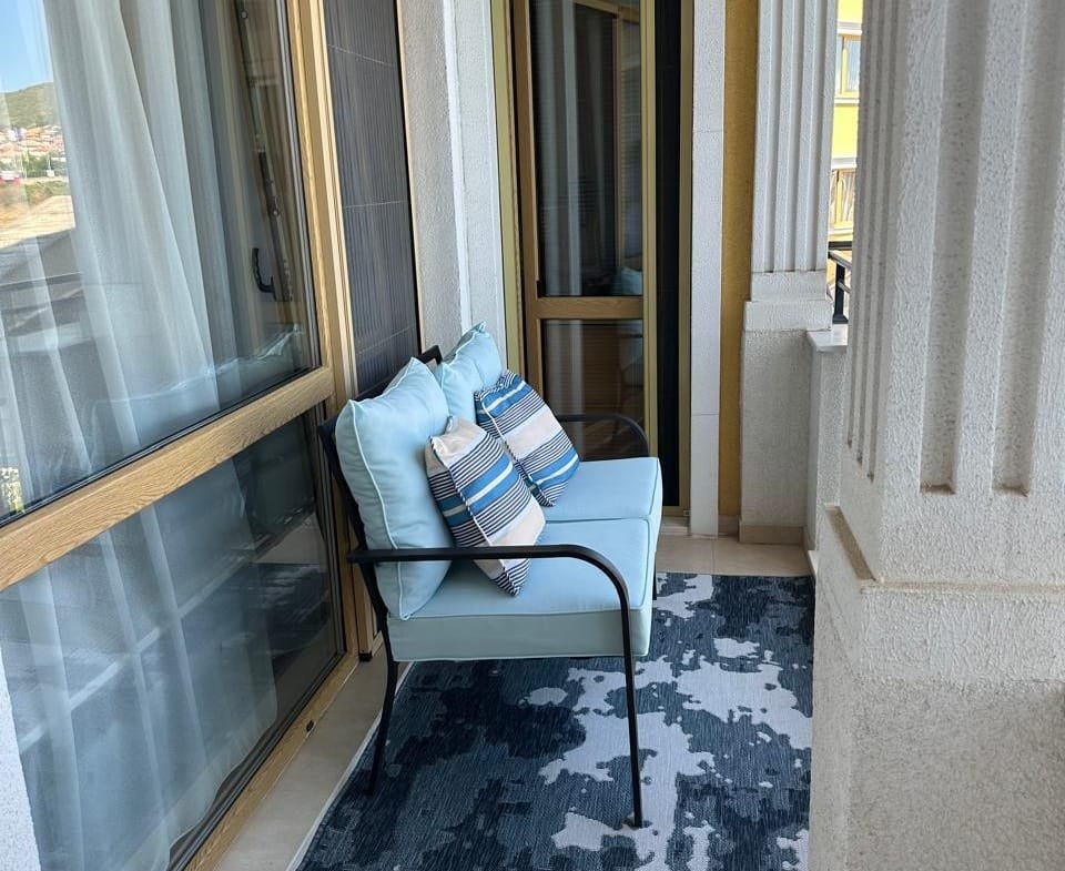 Уютный балкон с синей мебелью и декоративными подушками, идеальное место для отдыха в Болгарии.