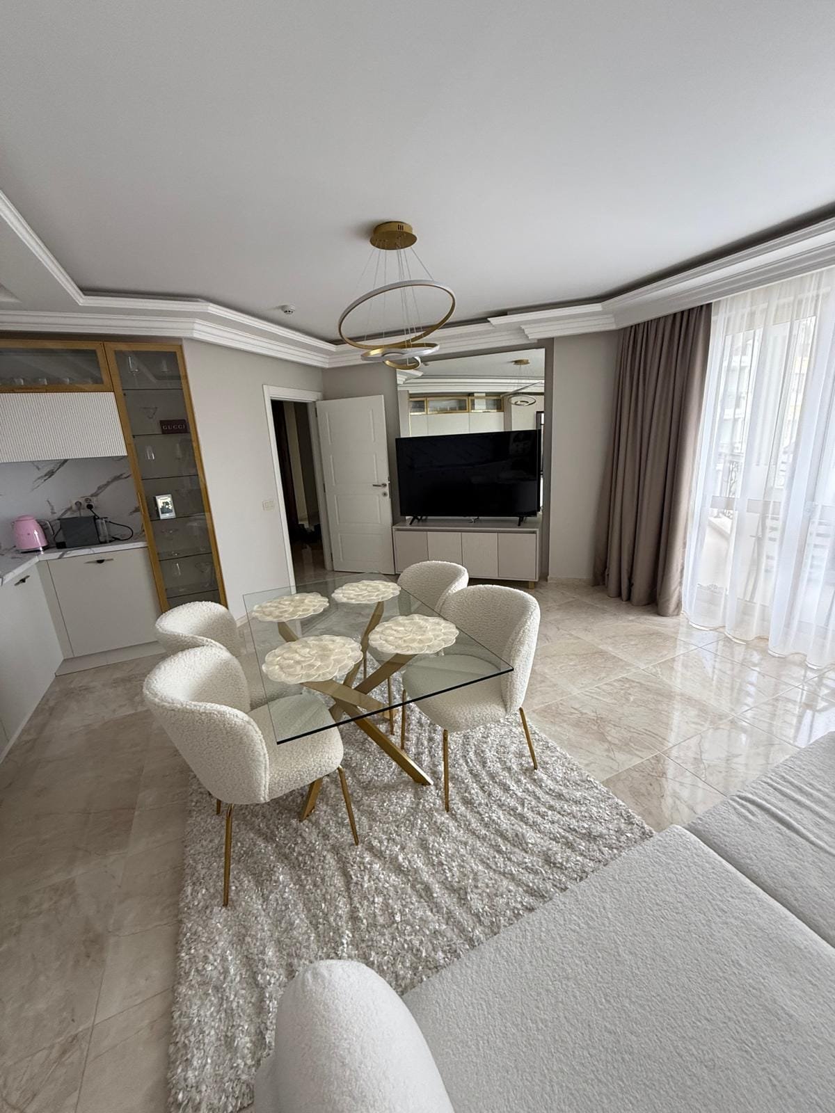 Современная квартира с стильной обстановкой, белыми креслами и стеклянным столом, подходит для покупки и аренды в Болгарии.