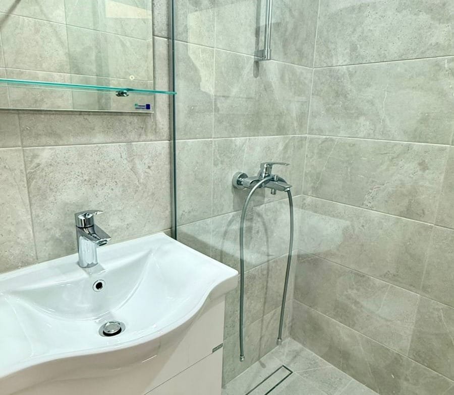 Современная ванная комната с душевой кабиной, стеклянными перегородками и раковиной для комфортной жизни в Болгарии.