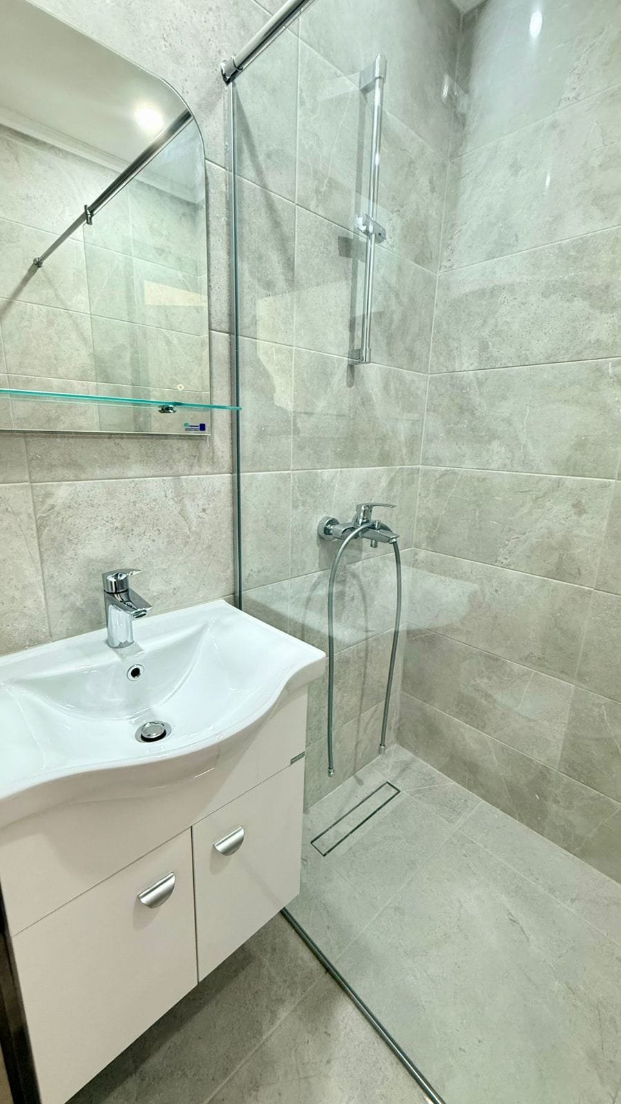 Современная ванная комната с душевой кабиной, стеклянными перегородками и раковиной для комфортной жизни в Болгарии.