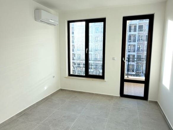 Пустая квартира с большими окнами, светлым интерьером и плиточным полом, готовая для продажи в Болгарии.