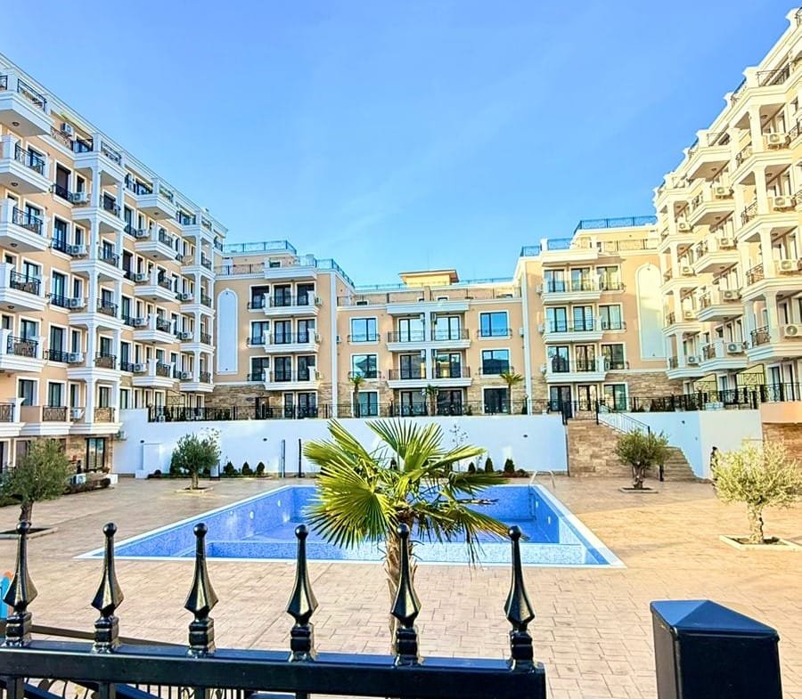 Современный жилой комплекс в Болгарии с бассейном и зелеными насаждениями, идеальный для покупки недвижимости у моря.