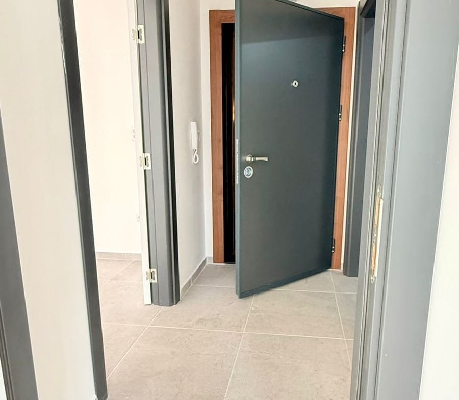 Современный вход в квартиру с раздвижными дверями, светлые стены и плитка на полу, подходящий для покупки недвижимости в Болгарии.