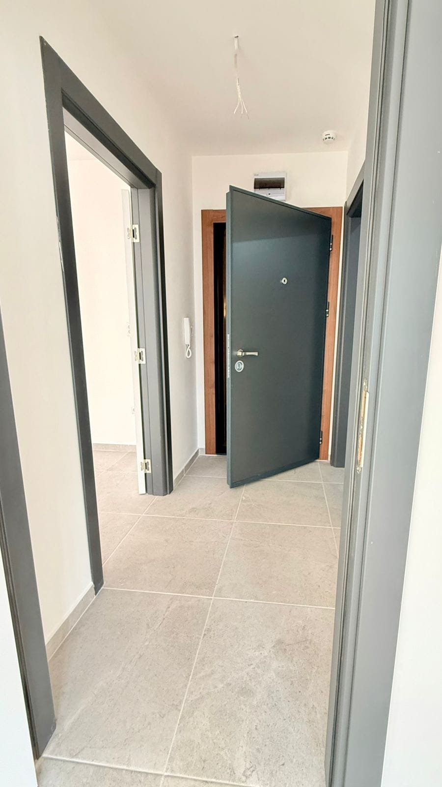 Современный вход в квартиру с раздвижными дверями, светлые стены и плитка на полу, подходящий для покупки недвижимости в Болгарии.