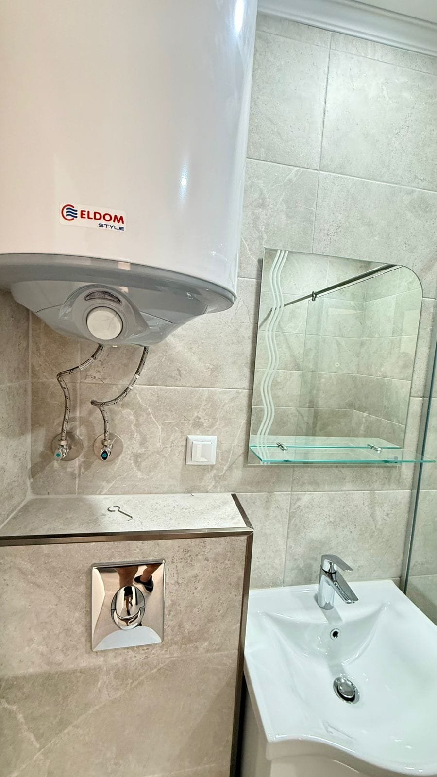 Современная ванная комната с бойлером, раковиной и зеркалом, подходящая для покупки недвижимости в Болгарии.