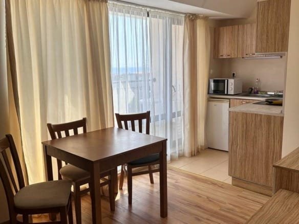 Современная кухня в Болгарии с деревянной мебелью, светлыми шторами и видом на море. Идеально для комфортной жизни и отдыха.