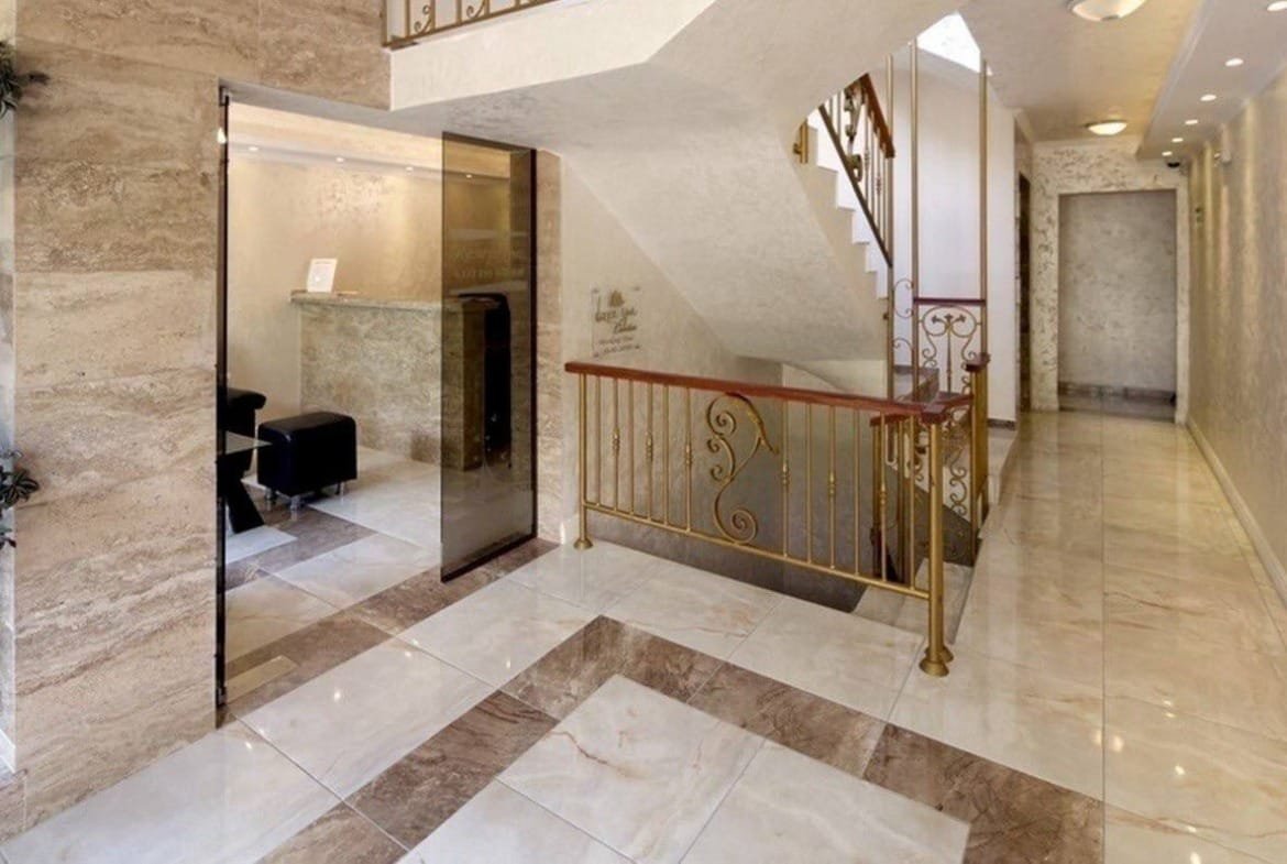 Современный холл с мраморным полом, лестницей и стильными элементами дизайна, идеальный для продажи недвижимости в Болгарии.