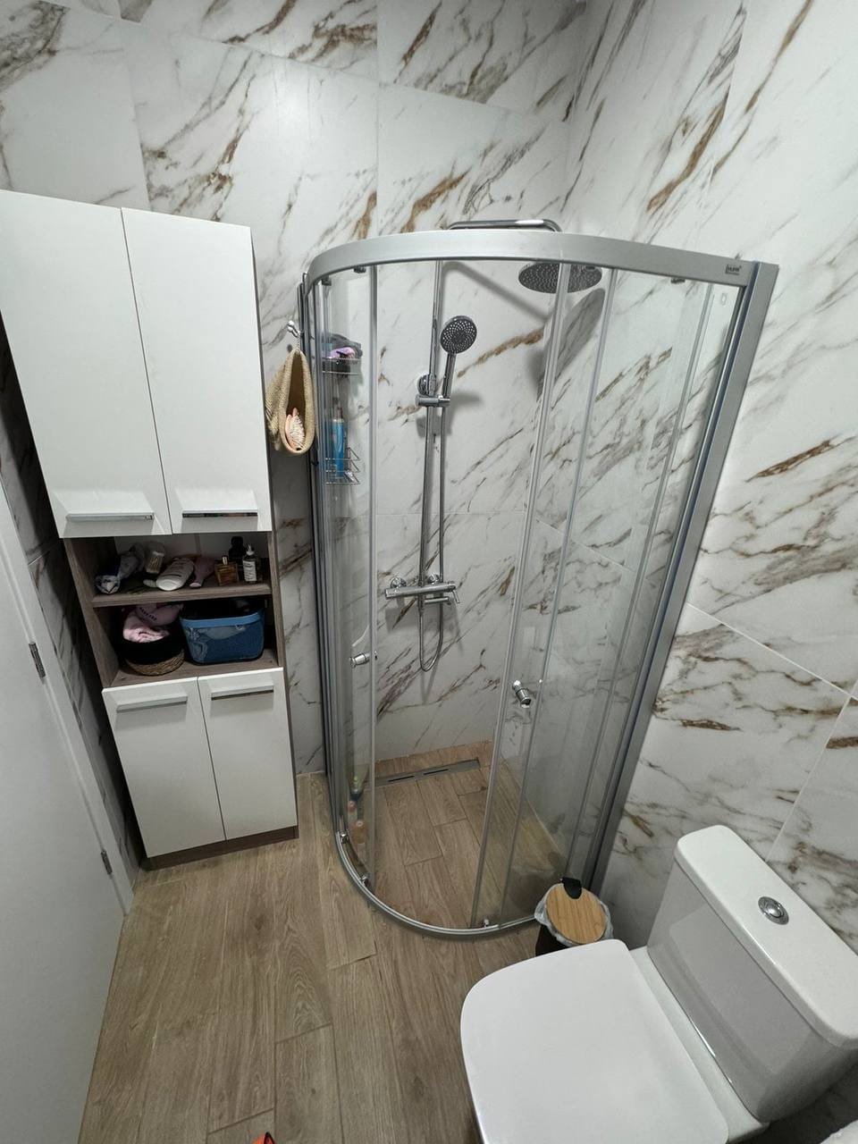 Современная ванная комната с душевой кабиной, сантехникой и стильным шкафом для хранения. Идеально для покупки недвижимости в Болгарии.