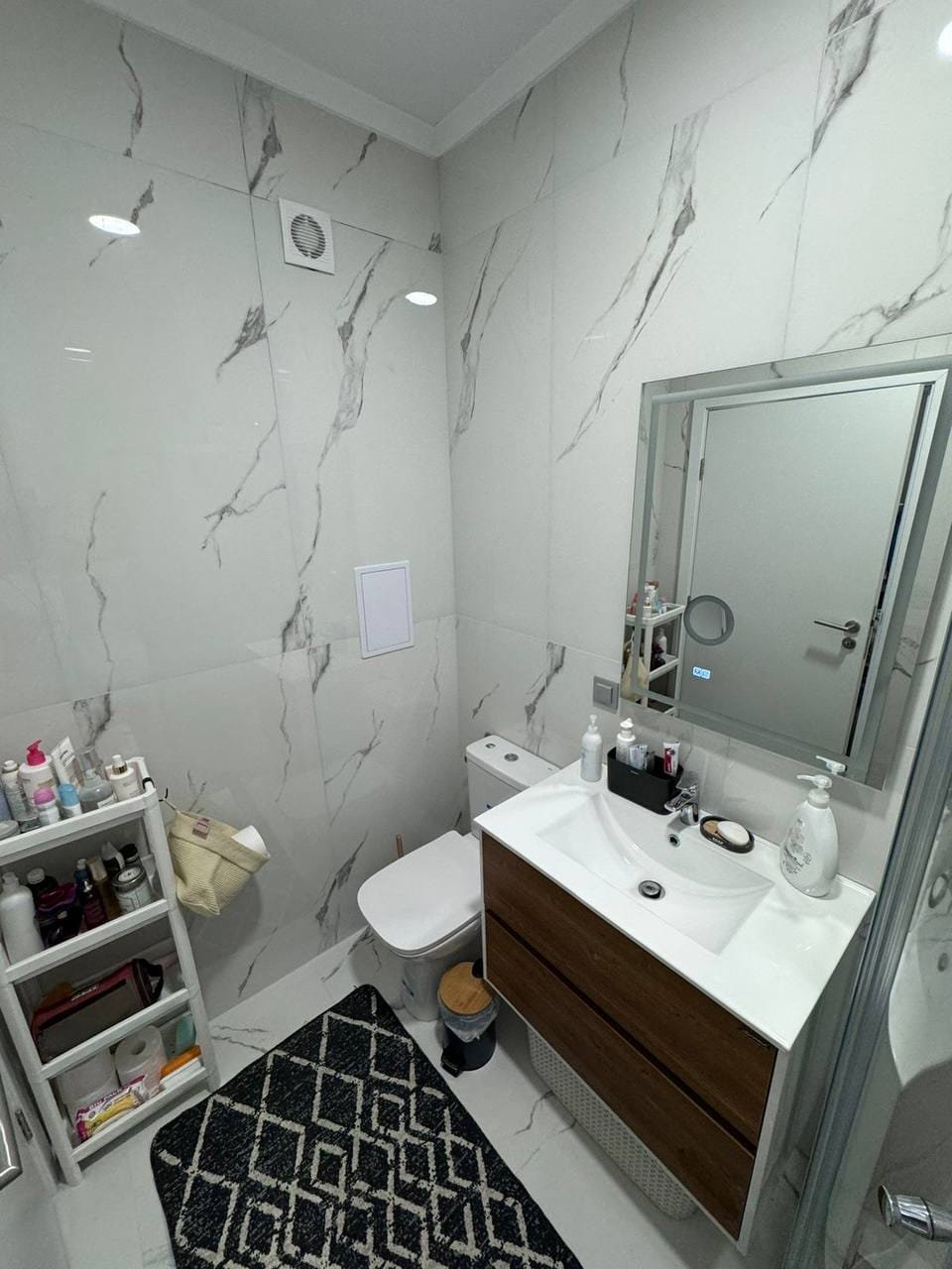 Современный санузел с белой плиткой, деревянным шкафчиком и зеркалом, идеально подходит для дома в Болгарии.