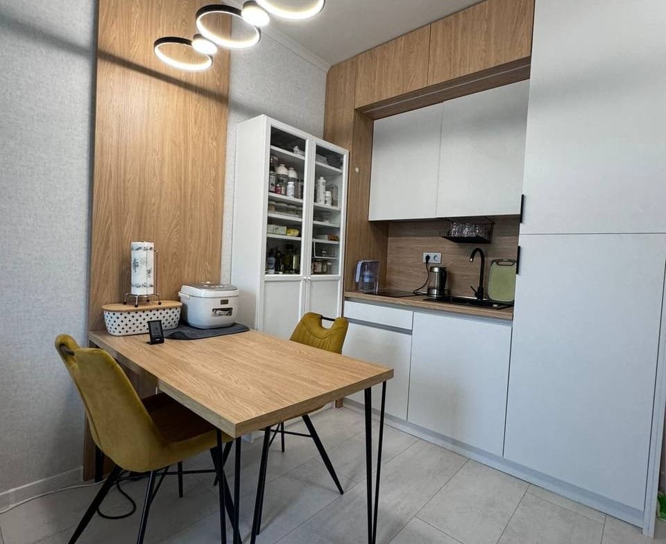 Современная кухня с деревянными элементами, столом и стульями, подходит для покупки недвижимости в Болгарии.